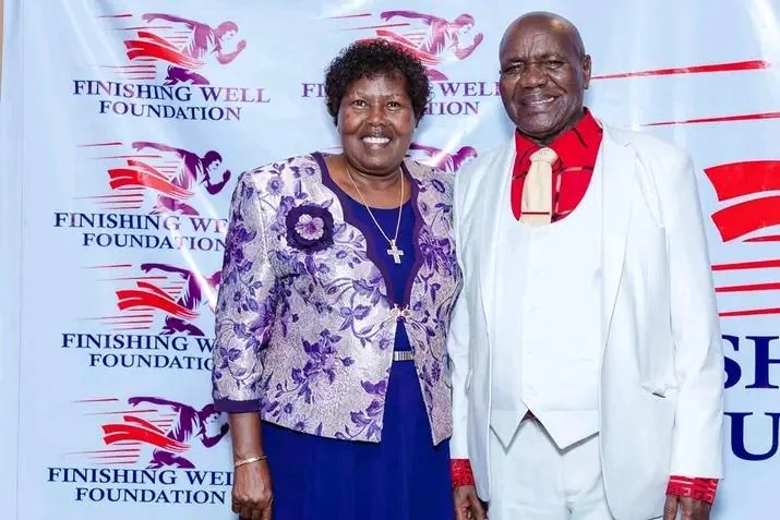 A smiling couple standing in front of a Finishing Well Foundation backdrop